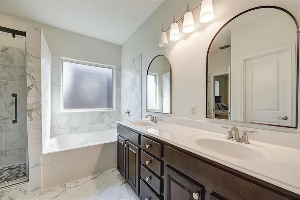 a bathroom with a double vanity sink mirror and bathtub