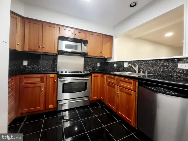 a kitchen with granite countertop a stove top oven microwave and cabinets