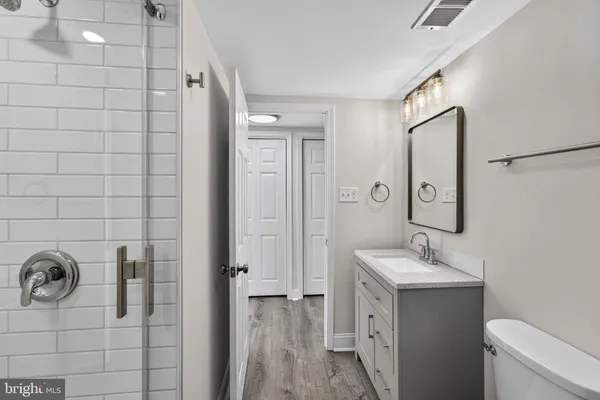 a bathroom with a double vanity sink a toilet and shower
