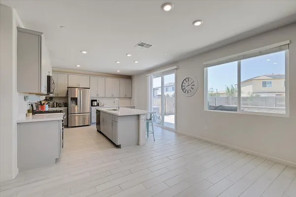 a kitchen with stainless steel appliances granite countertop a refrigerator a sink dishwasher a stove and white countertops with wooden floor