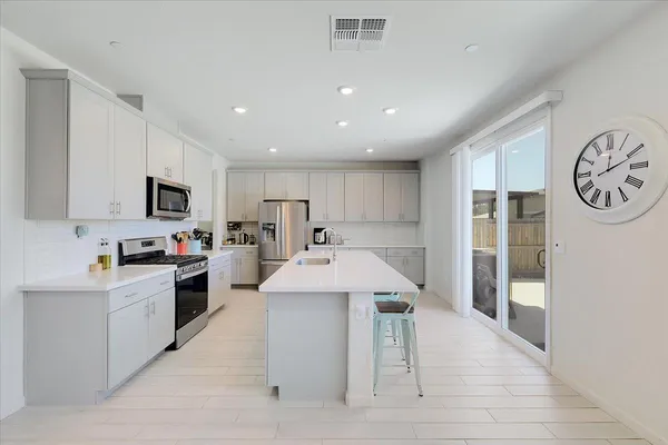 a kitchen with stainless steel appliances kitchen island granite countertop a refrigerator oven a sink dishwasher and white cabinets with wooden floor