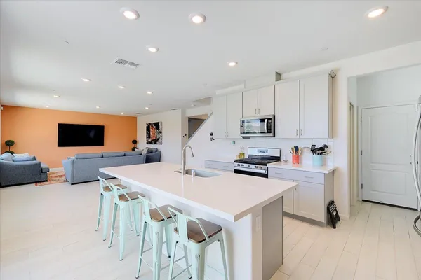 a kitchen with stainless steel appliances kitchen island a table chairs sink and microwave