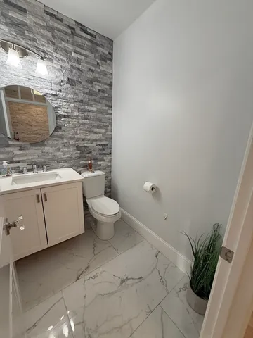 a bathroom with a granite countertop sink a toilet and a mirror