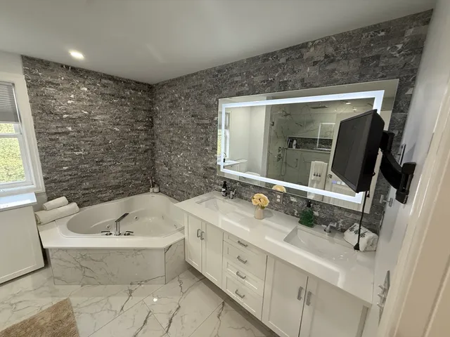 a bathroom with a double vanity sink mirror and bathtub