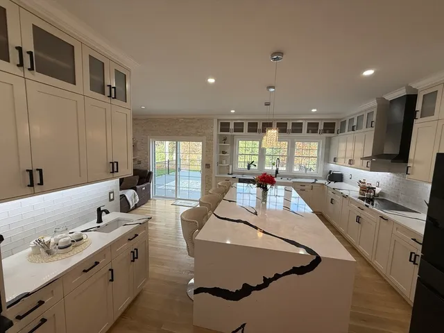 a large kitchen with kitchen island a large counter top space a sink a stove and a window