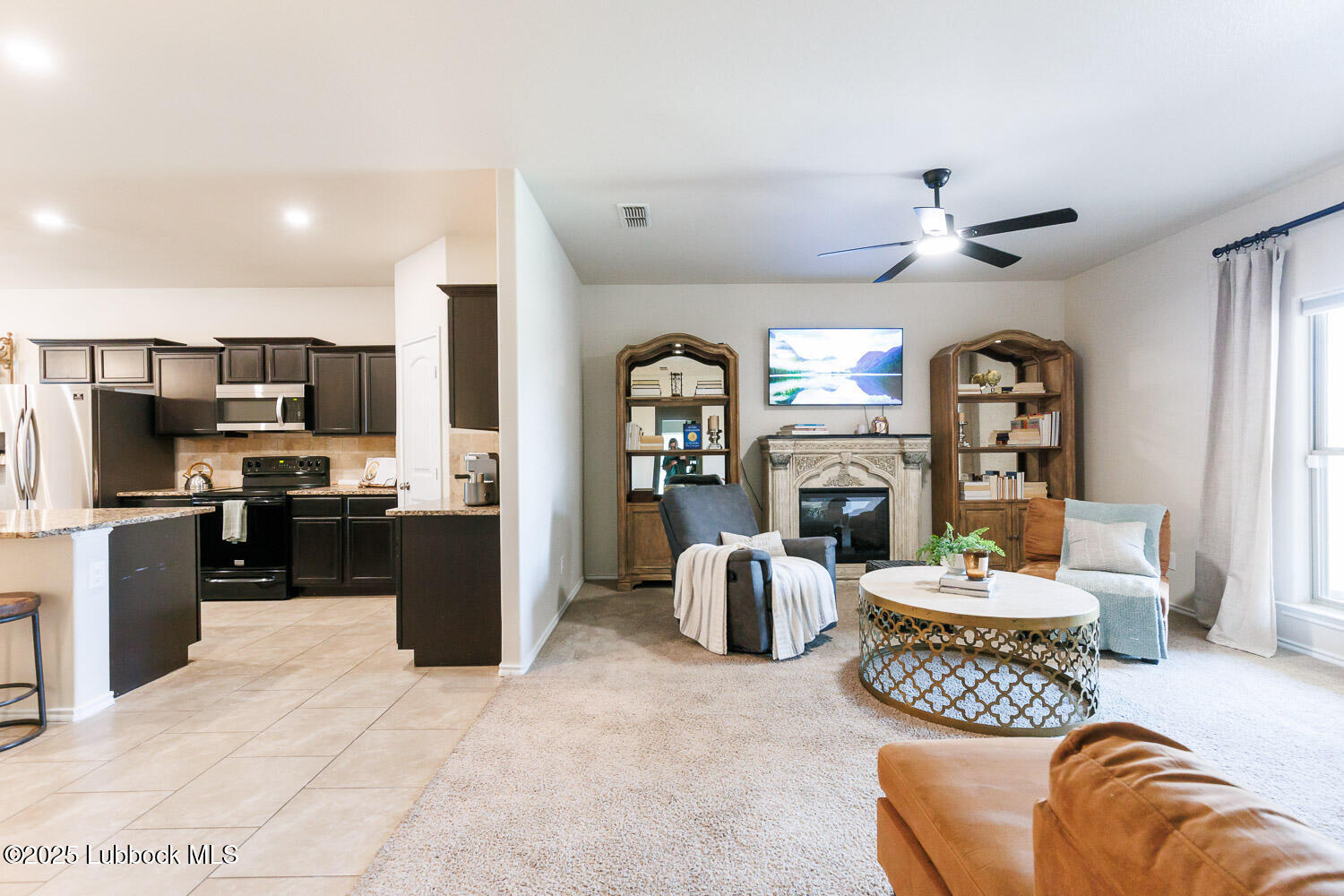 7348 100th Street Lubbock, TX 79424 - Photo 45 of 55 a living room with furniture a fireplace and a kitchen view