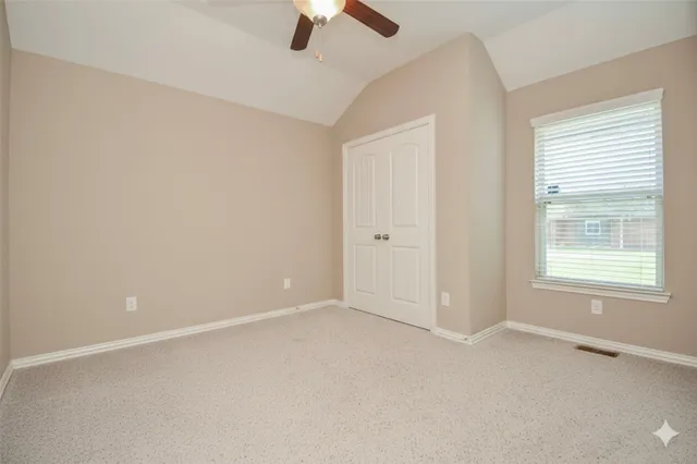 an empty room with a window and ceiling fan
