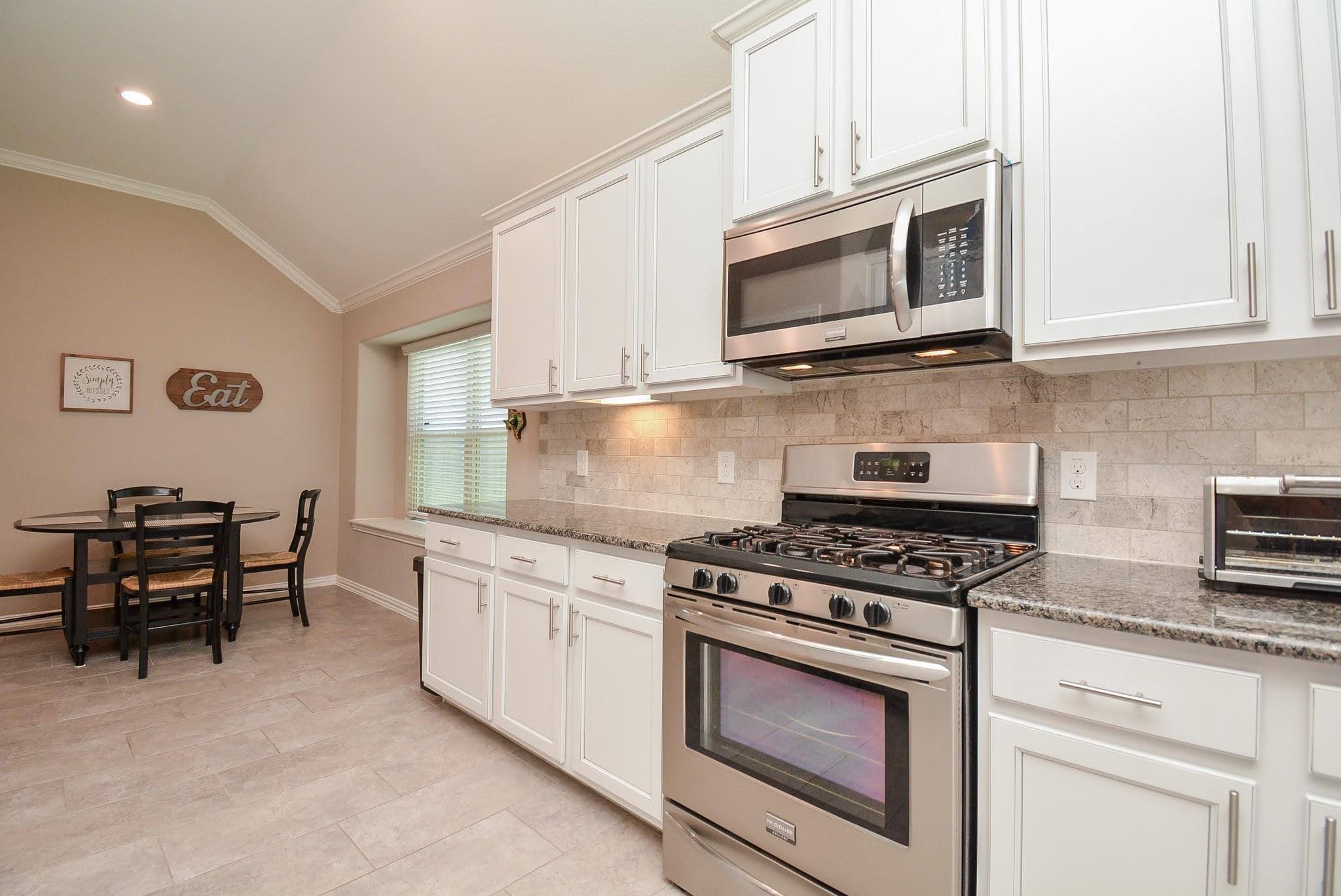 20414 Duncan Run Lane Cypress, TX 77433 - Photo 9 of 18 a kitchen with stainless steel appliances granite countertop a stove a microwave a sink and white cabinets