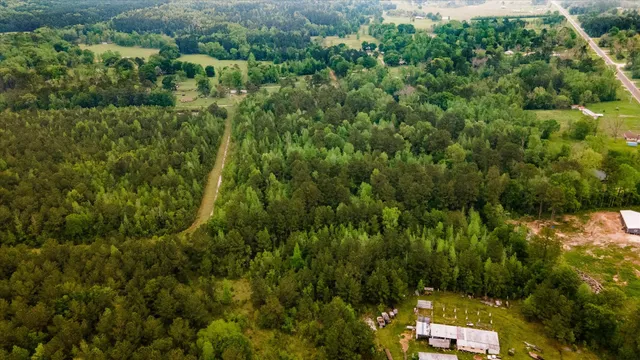 an aerial view of a house with a lush green forest
