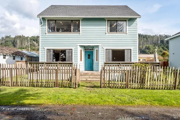 a white house that has tree in front of it