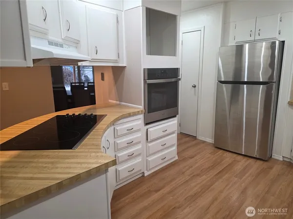 a kitchen with granite countertop a refrigerator and a stove top oven