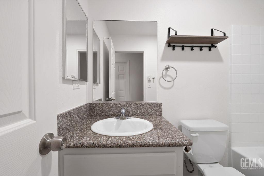 Undisclosed Address McFarland, CA 93250 - Photo 16 of 35 a bathroom with a granite countertop sink a toilet and a mirror