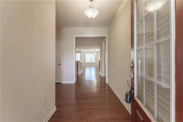 a view of a hallway with wooden floor and a bathroom
