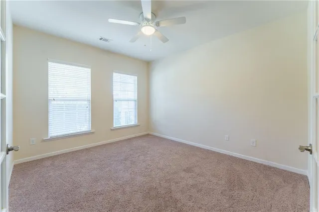 an empty room with a chandelier fan and windows