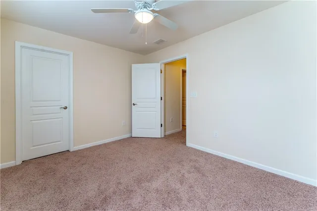 an empty room with a chandelier fan and windows
