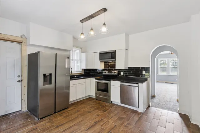 a kitchen with stainless steel appliances granite countertop a refrigerator a stove and a sink
