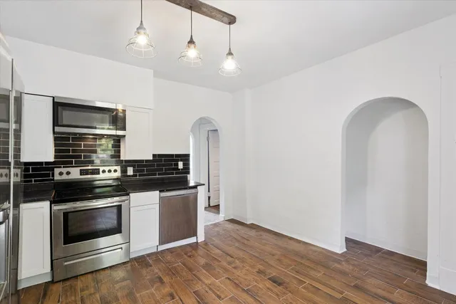 a kitchen with stainless steel appliances and wooden floor