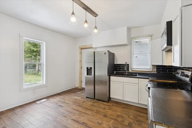 a kitchen with stainless steel appliances granite countertop a refrigerator a sink dishwasher a stove with wooden cabinets and floor