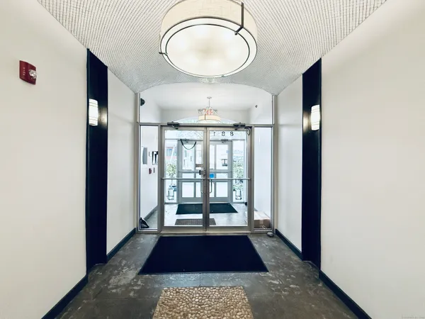 a hallway with wooden floor chandelier and a rug