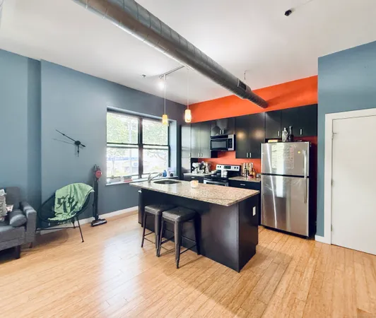 a kitchen with stainless steel appliances granite countertop a stove refrigerator and dining table with wooden floor