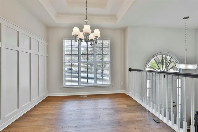 an empty room with wooden floor a ceiling fan and windows