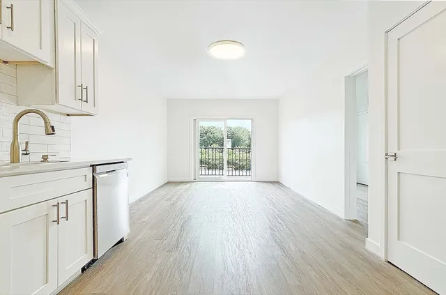a hallway with white cabinets and wooden floor