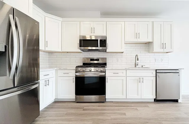 a kitchen with cabinets stainless steel appliances and a counter space
