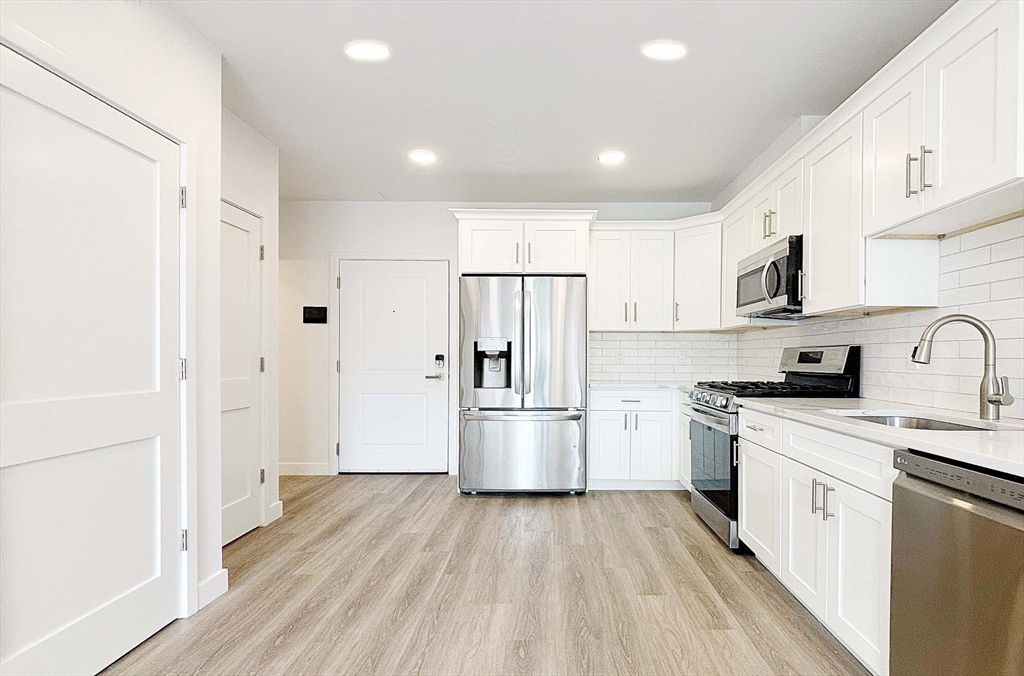 1133 North Shore Road, Unit 205 Revere, MA 02151 - Photo 8 of 16 a kitchen with a sink dishwasher a refrigerator and a stove top oven