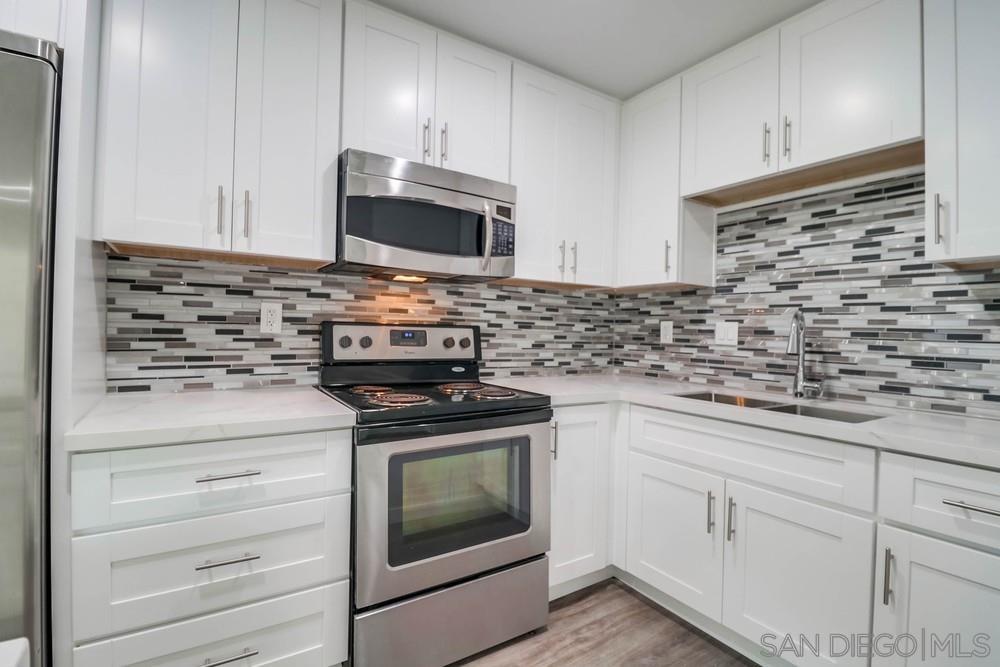 a kitchen with stainless steel appliances granite countertop white cabinets and a stove a oven with wooden floor