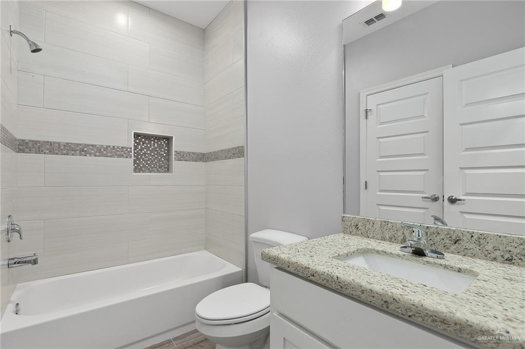 1908 Stauffers Street, Unit 1 Weslaco, TX 78596 - Photo 6 of 14 a bathroom with a granite countertop bathtub toilet sink and mirror