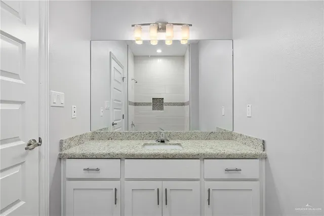 a bathroom with a granite countertop sink and a mirror