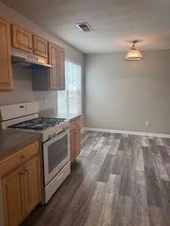 a kitchen with granite countertop a refrigerator and a stove top oven