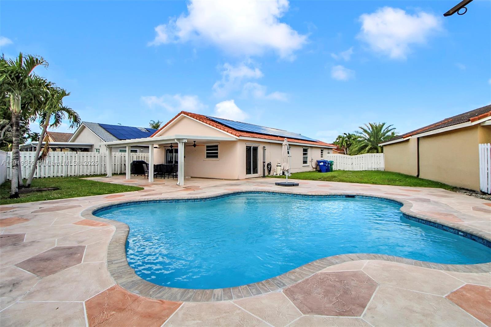 6122 Northwest 181st Terrace Circle West Hialeah, FL 33015 - Photo 21 of 28 a white house with a large pool and lawn chairs with wooden fence