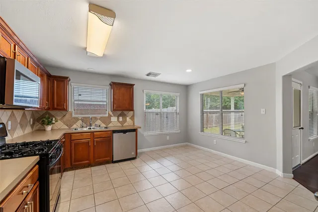a kitchen with stainless steel appliances granite countertop a stove a sink and a refrigerator