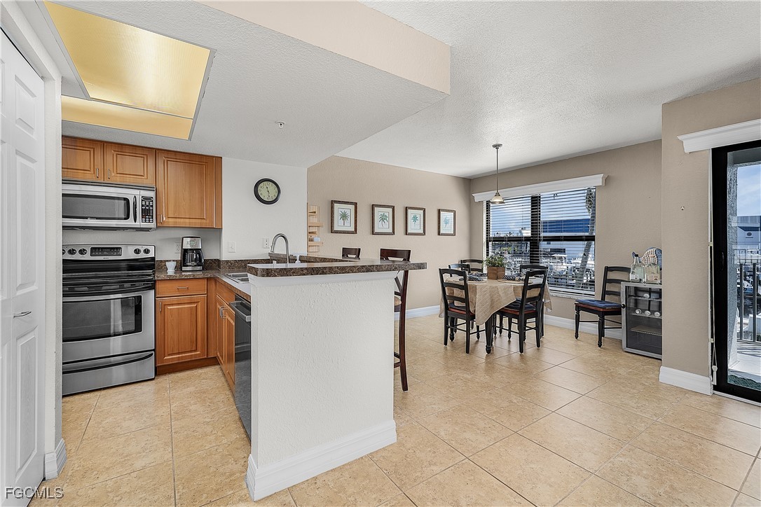 16641 Stringfellow Road, Unit 502 Bokeelia, FL 33922 - Photo 10 of 43 a kitchen with stainless steel appliances granite countertop a stove top oven a sink a dining table and chairs
