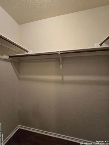 an empty room with wooden floor chandelier fan and windows