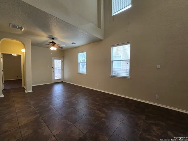 an empty room with wooden floor ceiling fan and windows