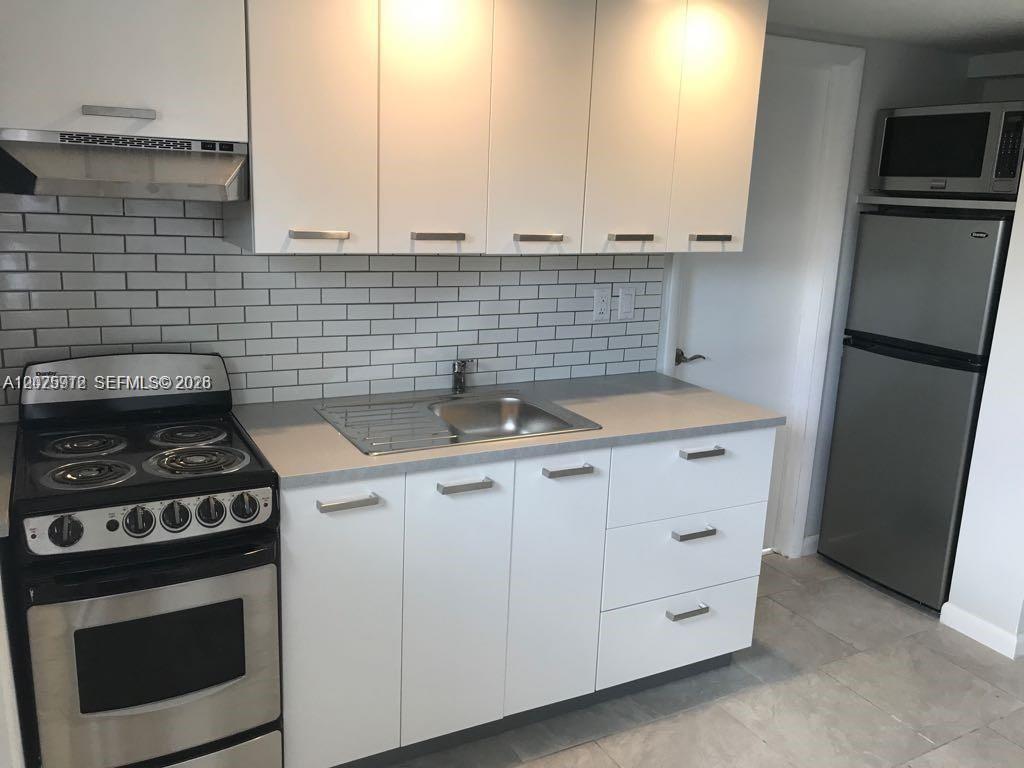 2224 Southwest 11th Street, Unit 3 Miami, FL 33135 - Photo 2 of 15 a kitchen with granite countertop a sink stove and cabinets