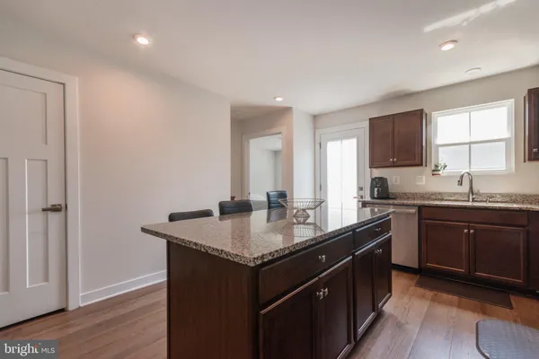a kitchen with granite countertop a refrigerator a sink a stove and chairs