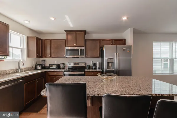a kitchen with stainless steel appliances granite countertop wooden floors a stove a microwave a sink and a refrigerator