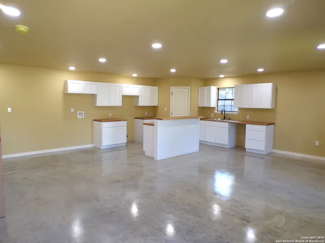 a view of a kitchen with kitchen island a sink a stove a counter top space and cabinets