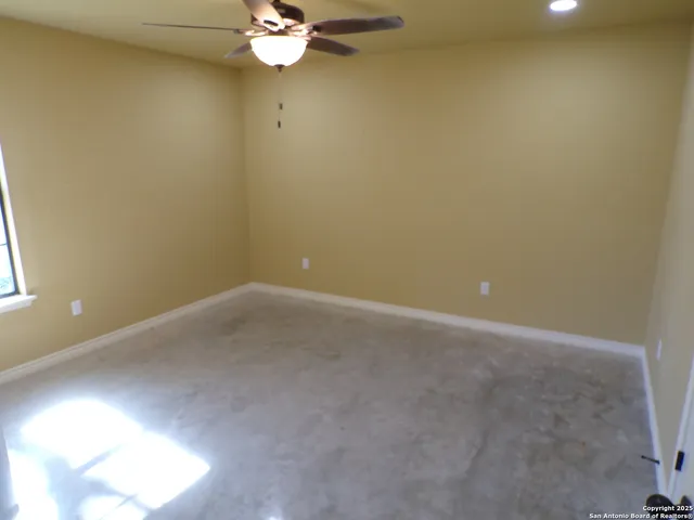 an empty room with a chandelier fan and windows