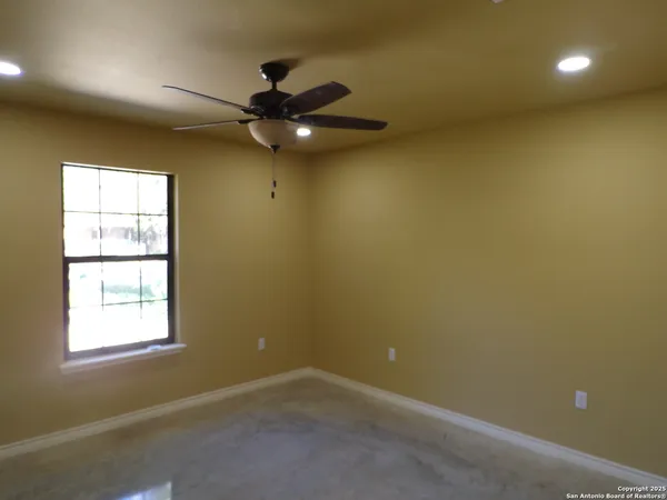an empty room with a window and a fan