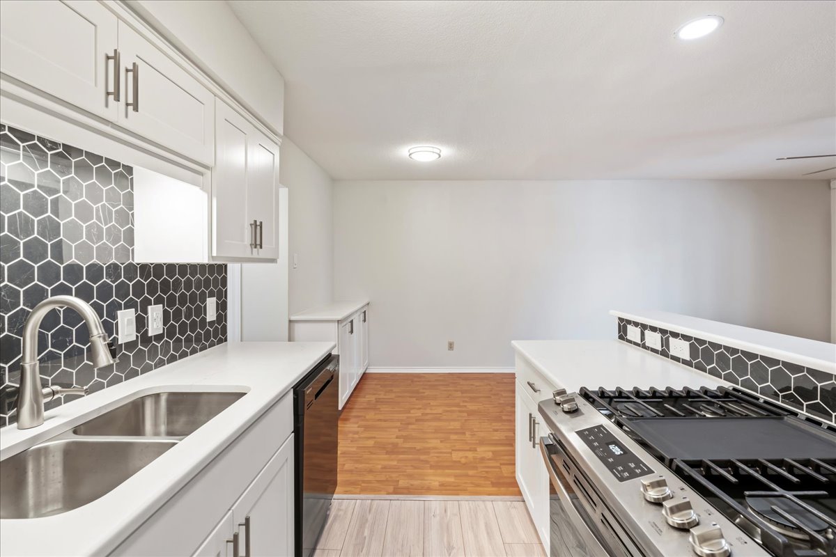 505 West 7th Street, Unit 313 Austin, TX 78701 - Photo 9 of 30 Kitchen featuring backsplash, dishwasher, stainless steel range with gas stovetop, a sink, and white cabinetry