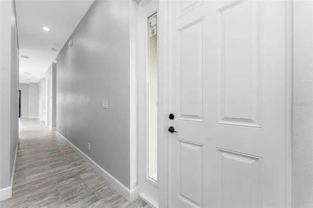 an empty room with wooden floor chandelier and windows