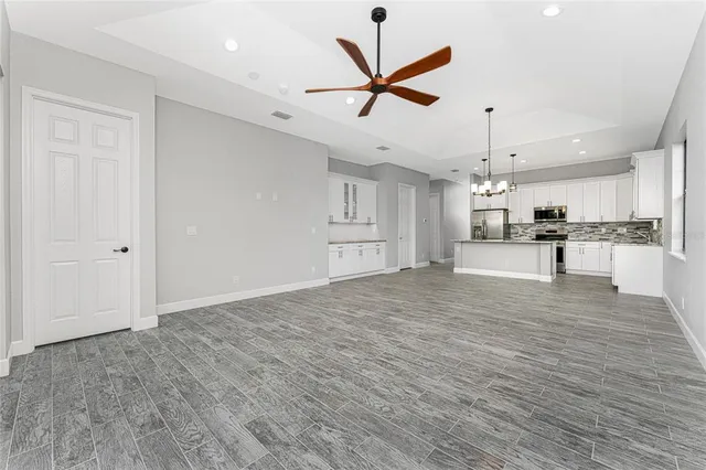 a large white kitchen with kitchen island a sink a center island and stainless steel appliances