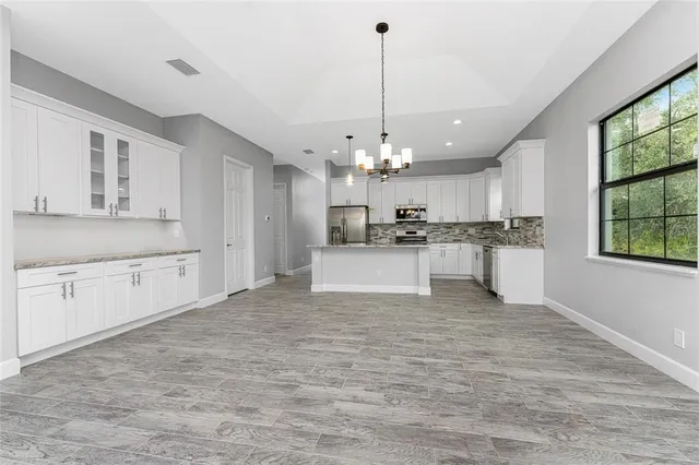a large kitchen with white cabinets stainless steel appliances and a chandelier