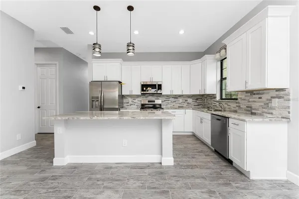 a large kitchen with stainless steel appliances kitchen island granite countertop a refrigerator a sink dishwasher a oven with a dining table and chairs