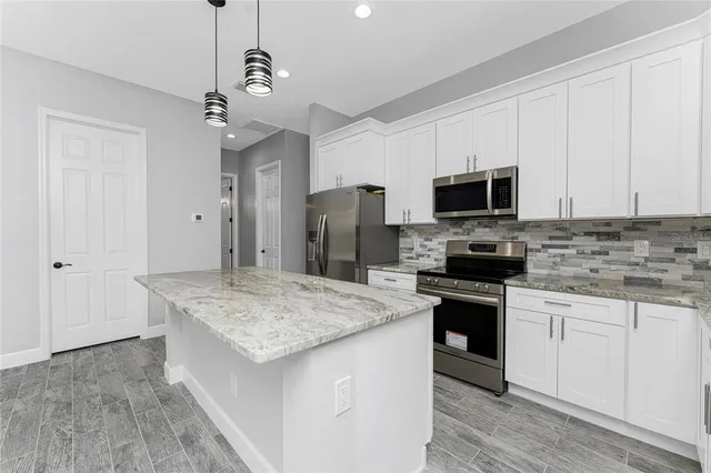 a kitchen with stainless steel appliances granite countertop a sink stove and wooden floor