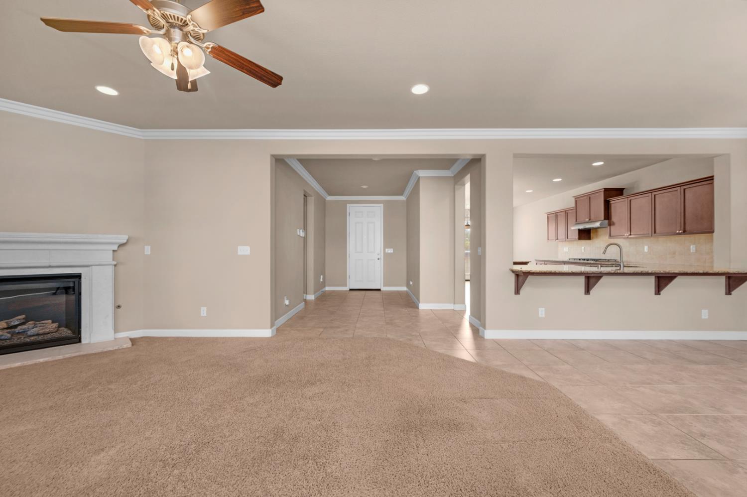 3267 Portals Avenue Clovis, CA 93619 - Photo 24 of 69 a view of a livingroom with a fireplace a ceiling fan and a kitchen view